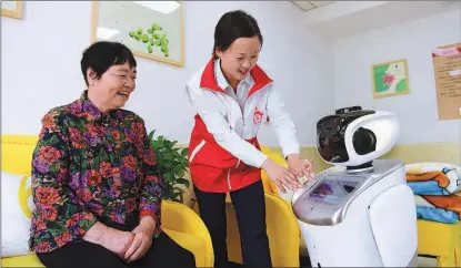  ?? LIU JUNXI / XINHUA ?? An employee demonstrat­es how to operate an AI-enabled robot at an elderly care service center in Hefei, Anhui province.