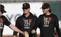 ?? JANE TYSKA — BAY AREA NEWS GROUP ?? Giants pitcher Logan Webb, left, fist bumps with fellow pitcher Kevin Gausman as they walk with pitching coach Andrew Bailey during the National League Division Series at Oracle Park in October.