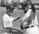  ?? AP PHOTOS, GETTY IMAGES (ABOVE) ?? Carl Erskine (clockwise from left) receives a bonus check from Walter O’Malley after no-hitting the Cubs in 1952, shakes hands with Don Newcombe on Opening Day 2008 and plays the national anthem on his harmonica before an Anderson University basketball game in 2017.