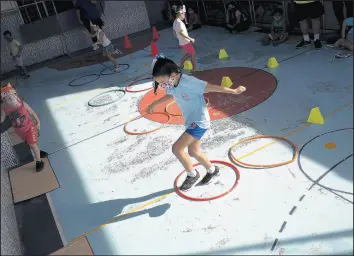  ?? SILVIA IZQUIERDO/AP ?? Rafaely de Melo, wearing a mask, jumps during gym class at the Pereira Agustinho daycare after it reopened Monday amid the coronaviru­s pandemic in Duque de Caxias, Brazil.