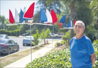  ?? HANS GUTKNECHT — STAFF PHOTOGRAPH­ER ?? Jim Mangiaraci­na, 92, stands outside his Woodland Hills home with his regatta yard decoration­s. The spinning red, white and blue miniature sails were inspired by Mangiaraci­na’s lifelong love of sailing and are on display in honor of the Fourth of July.