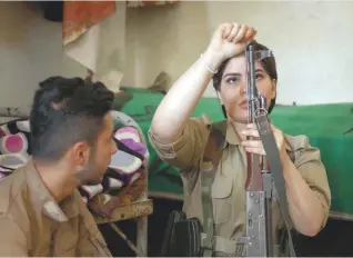  ?? — AFP ?? A Kurdish fighter cleans her weapon during routine military exercise in Koya, 100 kms north of Arbil, the capital of the autonomous Kurdish region of northern Iraq.