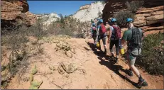  ?? BRIAN VAN DER BRUG/LOS ANGELES TIMES FILE PHOTOGRAPH ?? A group of canyoneers hikes up red sandstone to the entry point for Keyhole Canyon in Zion National Park, Utah, on Sept. 19, 2015.
