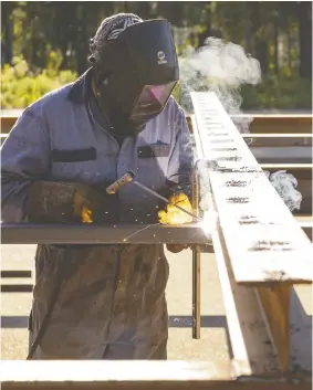  ?? RANDY VANDERVEEN / POSTMEDIA NEWS FILES ?? Smoke rises around a welder as he fits together the metal making up the skeleton of a new drive-in theatre screen built this summer in Evergreen Park. The Investment and Growth Strategy is aimed at diversifyi­ng Alberta's economy.