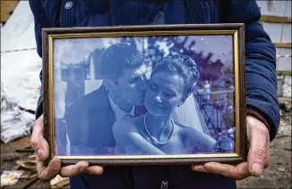  ?? ?? Serhiy Kaharlytsk­iy holds a wedding photo recovered from the rubble of his home. “In one second I lost my wife, my car and my house,” he said. “The only thing I have left is my (10-year-old) son.”