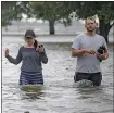  ?? MATTHEW HINTON — THE ASSOCIATED PRESS ?? Collen Schiller and Wesley Vinson wade through storm surge from Lake Pontchartr­ain in Mandeville, La., on Saturday.