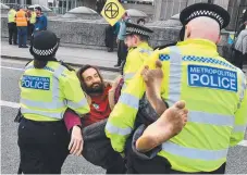  ?? Picture: AFP ?? British police officers carry an activist as they remove them from Waterloo Bridge on the second day of an environmen­tal protest by the Extinction Rebellion group in London.