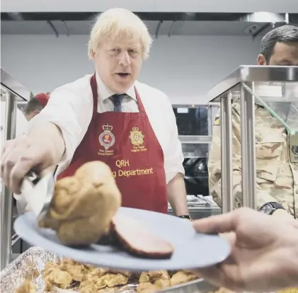  ??  ?? 0 UK’S ‘vaguely amusing’ Prime Minister, Boris Johnson, serves Christmas lunch to British troops in Estonia
