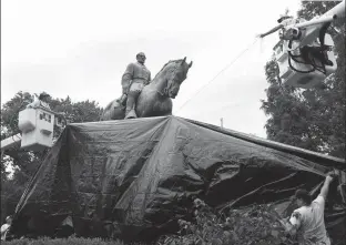  ?? Associated Press ?? City workers drape a tarp Wednesday over the statue of Confederat­e General Robert E. Lee in Emancipati­on Park in Charlottes­ville, Va. The move to cover the statues is intended to symbolize the city’s mourning for Heather Heyer, killed while protesting...