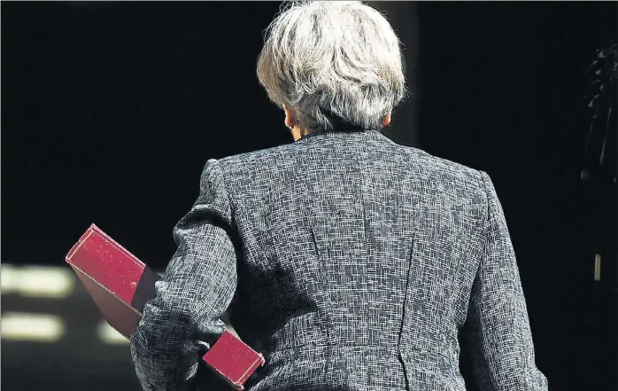  ??  ?? La ‘premier’ británica Theresa May camina de espaldas hacia el 10 de Downing Street tras su reunión con los partidos norirlande­ses.