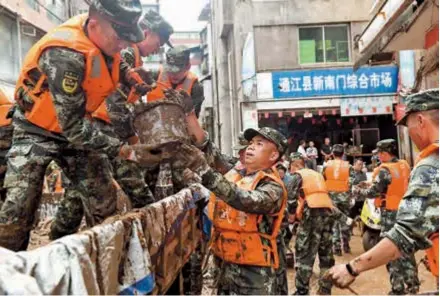  ?? — IC ?? Rescuers clear sludge in Bazhong City, southwest China’s Sichuan Province, yesterday after floods hit the city. Floodwater­s have inundated 4,578 hectares of crops and damaged 204 houses in Sichuan.