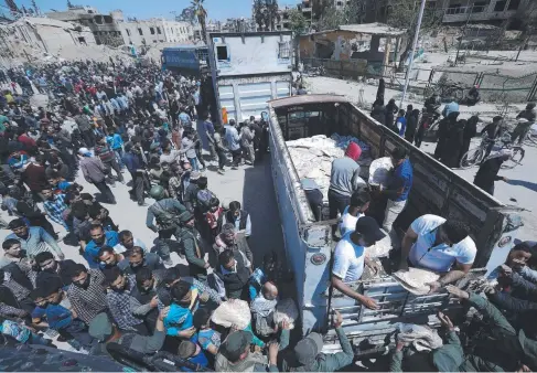  ?? HAPLESS VICTIMS: Civilians in the stricken Syrian city of Douma line up for food following recent air strikes by US, French and British forces. ??