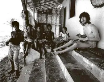  ??  ?? Mick Jagger toca tambor na varanda de uma casa em Arembepe, em 1968; acima, o músico toca violão para a então namorada, Marianne Faithfull, o filho dela, Nicholas, e moradores