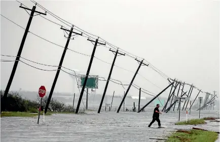  ?? ADREES LATIF ?? A man walks through floods waters and onto the main road after surveying his property which was hit by Hurricane Harvey in Rockport, Texas.