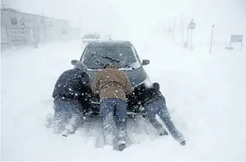  ?? JULIO CORTEZ/THE ASSOCIATED PRESS ?? A group of men help a motorist after his vehicle was stuck in the snow in Asbury Park, N.J. A massive winter storm swept from the Carolinas to Maine, dumping snow along the coast and bringing strong winds that will usher in possible record-breaking cold.