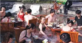  ?? — AFP ?? A staff member pouring jujubes or red dates into a hot spring as diners in the pool enjoy hotpot meals in Hangzhou in China’s eastern Zhejiang province.