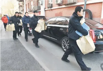  ??  ?? Police investigat­ors carry bags of evidence out of an elementary school in Beijing.