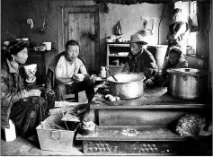  ??  ?? A woman and her family having a breakfast consisting of yak butter tea and tsampa in their kitchen in Zhaba.