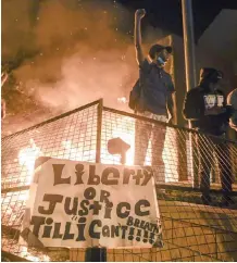  ?? EPA-EFE ?? A PROTESTER cheers as fire burns outside a Minneapoli­s police precinct during protests over the arrest of George Floyd, who later died in police custody, in Minneapoli­s. |