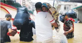  ?? (Navesh Chitrakar/Reuters) ?? A MAN carrying a child walks toward the dry ground from a flooded colony in Kathmandu last week.