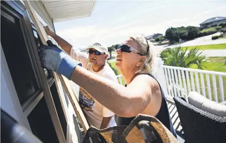  ?? JOSH MORGAN/USA TODAY NETWORK ?? Angie Travis and her husband, Jeff, cover the windows of their vacation home Tuesday in North Myrtle Beach, S.C., as Hurricane Florence advances on the East Coast.