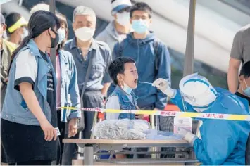  ?? MARK SCHIEFELBE­IN/AP ?? A worker clad in a protective suit swabs a child’s throat for COVID-19 testing Wednesday in Beijing.