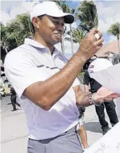  ?? JOE CAVARETTA/STAFF PHOTOGRAPH­ER ?? Tiger Woods shares a smile with fans as he signs autographs on Wednesday.