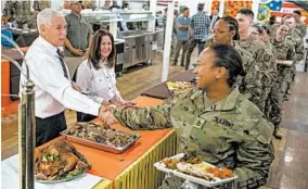  ?? ANDREW HARNIK/AP ?? Vice President Mike Pence, left, and his wife, Karen Pence, second from right, serve turkey for the Thanksgivi­ng holiday to troops on Saturday at Al Asad Air Base, Iraq.