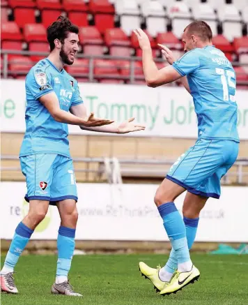  ??  ?? Finn Azaz (left) celebrates scoring Cheltenham’s second goal with Will Boyle