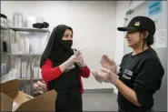  ?? ?? Marjan Enayt, 18, right, who is also a recent refugee from Afghanista­n, claps excitedly as Madina Safi, 28, lets her know they have finished unloading loaves of bread, as Safi trains Enayt in the bakery department at Giant, a grocery store in Alexandria, Va., Thursday, April 14, 2022. Safi and her family were evacuated from Afghanista­n and are trying to make a new life in the U.S., while in immigratio­n limbo.