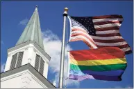  ?? Charlie Riedel / Associated Press ?? In this 2019 photo, a gay pride rainbow flag flies along with the U.S. flag in front of the Asbury United Methodist Church in Prairie Village, Kan. Conservati­ve leaders within the United Methodist Church unveiled plans Monday to form a new denominati­on, the Global Methodist Church, with a doctrine that does not recognize same-sex marriage.