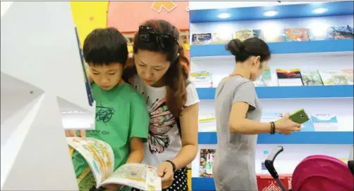  ?? DA WEI / CFP ?? A young reader and his mother look at publicatio­ns at a Beijing book fair.