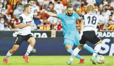 ?? Agence France-presse ?? ↑
Real Madrid’s Karim Benzema (centre) vies for the ball with Valencia’s Daniel Wass during their Spanish League match.