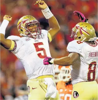  ?? STREETER LECKA/GETTY IMAGES ?? FSU QB Jameis Winston, left, celebrates with Devonta Freeman after throwing a touchdown. Winston riddled Clemson, throwing for 444 yards and 3 touchdowns and boosting his own Heisman Trophy stock.