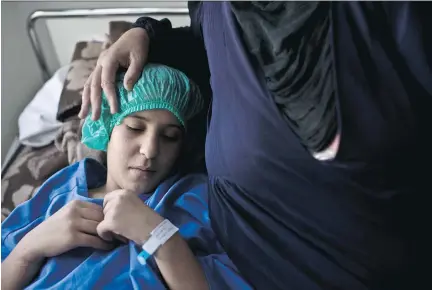  ?? MUHAMMED MUHEISEN/THE ASSOCIATED PRESS ?? Salam Rashid, 14, of Syria, who lost both of her legs below the knees, is comforted by her mother shortly before a surgery to reshape her stumps for prostheses at the MSF Hospital for Specialize­d Reconstruc­tive Surgery in Amman, Jordan.