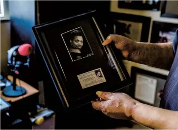  ?? ARIANA DREHSLER ?? William “Tayari” Howard holds a frame with a photo and business card of his mom, Dorothy Howard, who was a disc jockey known as “Louisville Lou.” She was a groundbrea­ker in Black radio in Kentucky.