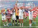  ??  ?? United States midfielder Lindsey Horan (9) hoists the World Cup trophy and celebrates with teammates.