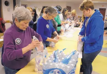  ?? GREG SORBER/JOURNAL ?? Teresa Fisher, Barbara du Lin and Kate Page, from left, assemble emergency preparedne­ss kits for homebound seniors as part of an MLK Day of Service project adopted by Senior Corps volunteers and AmeriCorps VISTA members.