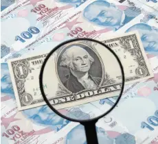  ?? — Reuters ?? A US dollar banknote is seen through a magnifying lens on top of 100 Turkish lira banknotes.
