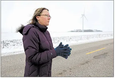  ?? AP file photo ?? Dorenne Hansen of Glenville, Minn., stands on a rural highway near a wind turbine in a field near Northwood, Iowa, in January. Opponents of wind power are successful­ly stalling or rejecting wind-farm projects across the country.