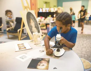  ?? JANE THERESE/SPECIAL TO THE MORNING CALL ?? Darnell Mack, 8, of Allentown looks through a microscope to examine the visual display at Allentown Art Museum’s American Galleries Exhibition opening ceremonies August 27.