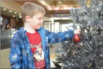  ??  ?? Bottom: Max Turcotte hangs an ornament on the Postcard Portables Christmas tree Saturday at the Medicine Hat Lodge.