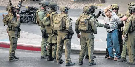  ?? L.E. Baskow Las Vegas Sun ?? SWAT OFFICERS take an unidentifi­ed suspect into custody. An explosive device was used to break the bus windows before he gave up.