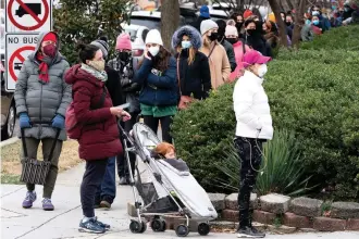  ?? The Associated Press ?? ■ People stand in a line spanning several blocks for COVID-19 testing on Tuesday at a Curative testing kiosk outside an elementary school in northwest Washington.