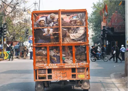  ??  ?? HUDDLED TOGETHER
in the back of a mini truck, a group of Muslims moves to safety in North East Delhi on February 26.