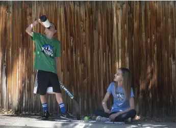  ?? Rachel Woolf, Special to The Denver Post ?? Jacoby Amos, 11, left, drinks water as his sister, Izzy Amos, 13, takes a break from playing street hockey on Friday in Littleton.