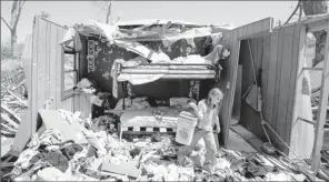  ?? By Jaime Green, AP ?? Tornado destructio­n: Sarah Gunter, 6, finds an unopened container of cat litter while sifting through her bedroom in Wichita on Monday. A tornado hit Saturday night with winds of 136 to 165 mph.