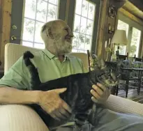  ?? BY ROXIE BEEBE-CENTER ?? Bruce Sloane relaxes with his cat at his Rappahanno­ck home, where he’s able to hear much more these days.