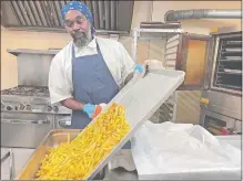  ?? ?? Mark McQuillar, the 55-year-old kitchen manager at the New London Community Meal Center on Montauk Avenue, unloads a tray of fries on Friday.