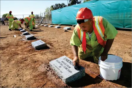  ?? RICH PEDRONCELL­I — THE ASSOCIATED PRESS ?? Steven Abujen, a California prison inmate with the Prison Industry Authority, cleans one of the newly installed headstones at the Mormon Island Relocation Cemetery near Folsom in October 2011. Lawmakers in Nevada and California are advancing legislatio­n to remove involuntar­y servitude from their state constituti­ons, a move that follows four states that purged forced labor from the books in ballot measures last fall.